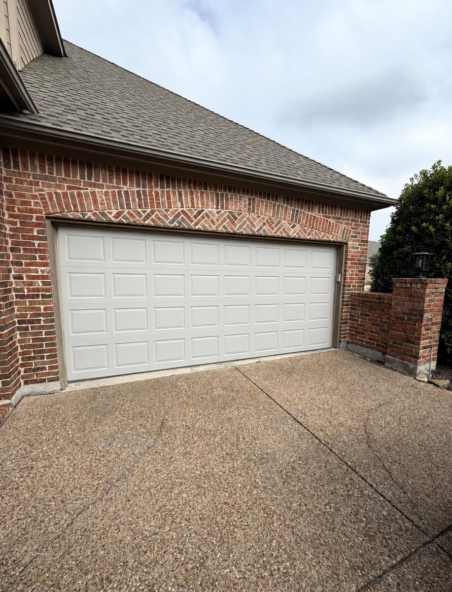 White raised short-panel garage door on a red brick home before replacement