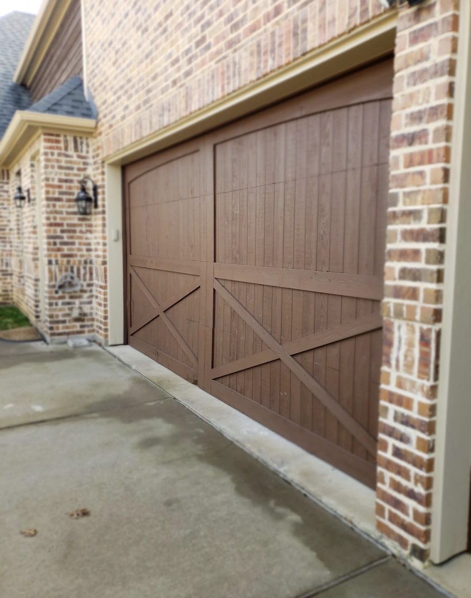 Custom stained cedar garage door with arched top and X-bracing