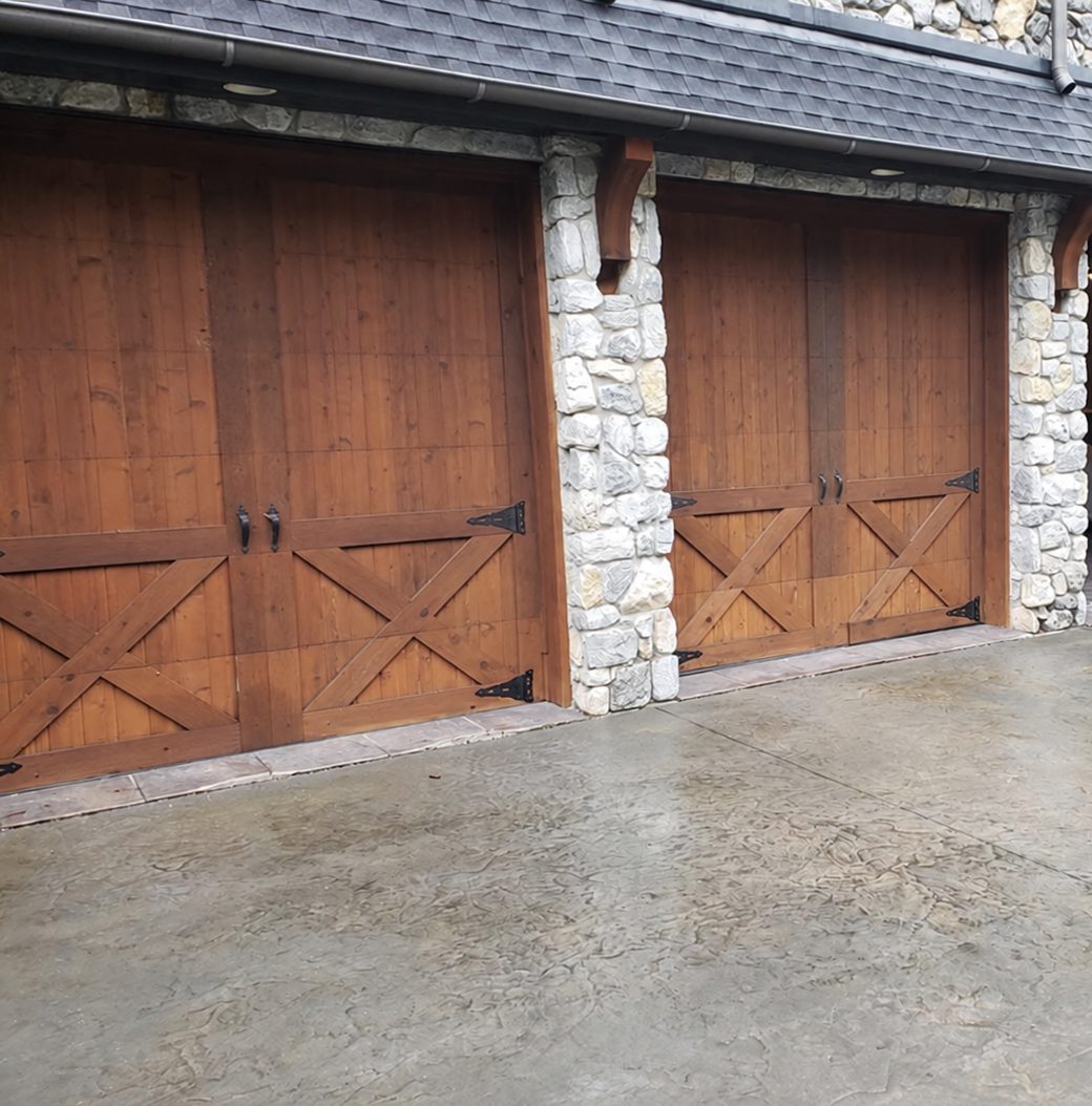 Stained cedar carriage-house doors with strap hinges between stone columns