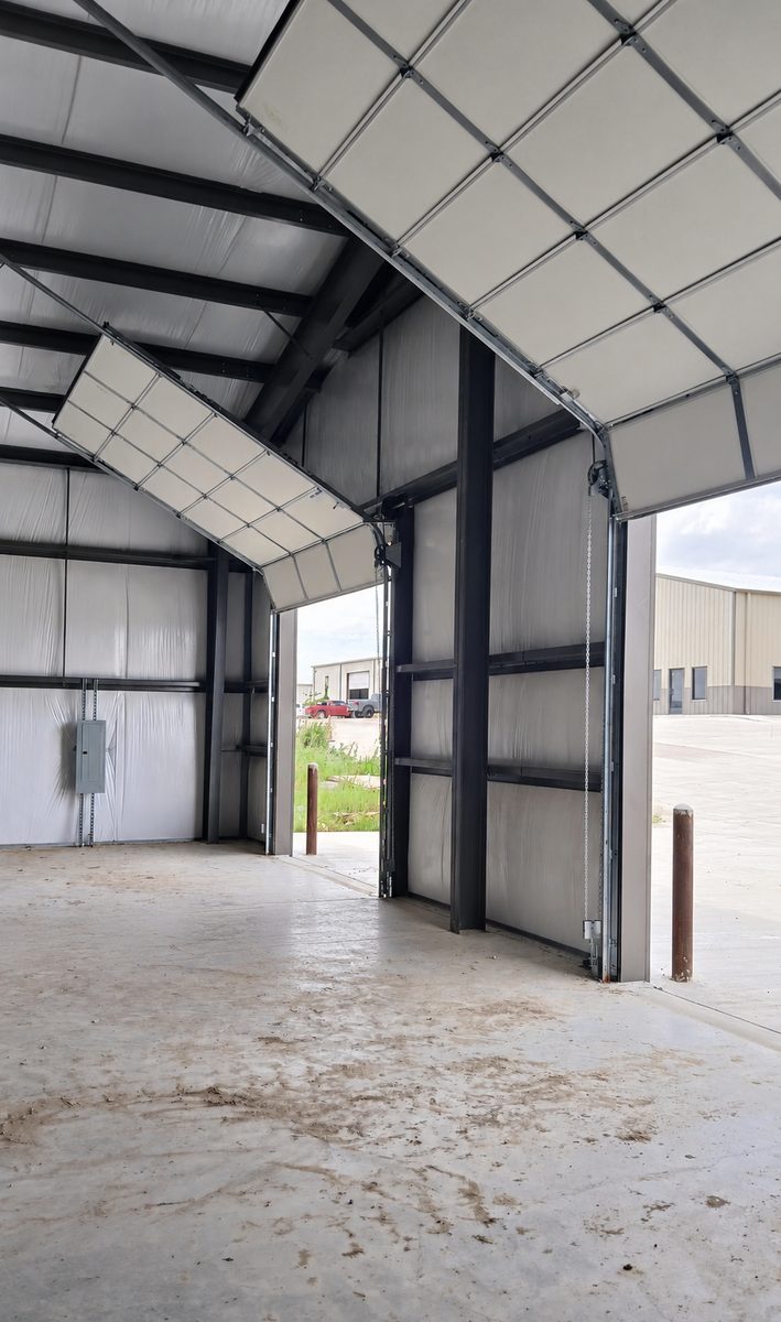 Commercial overhead sectional door part-raised inside a steel building