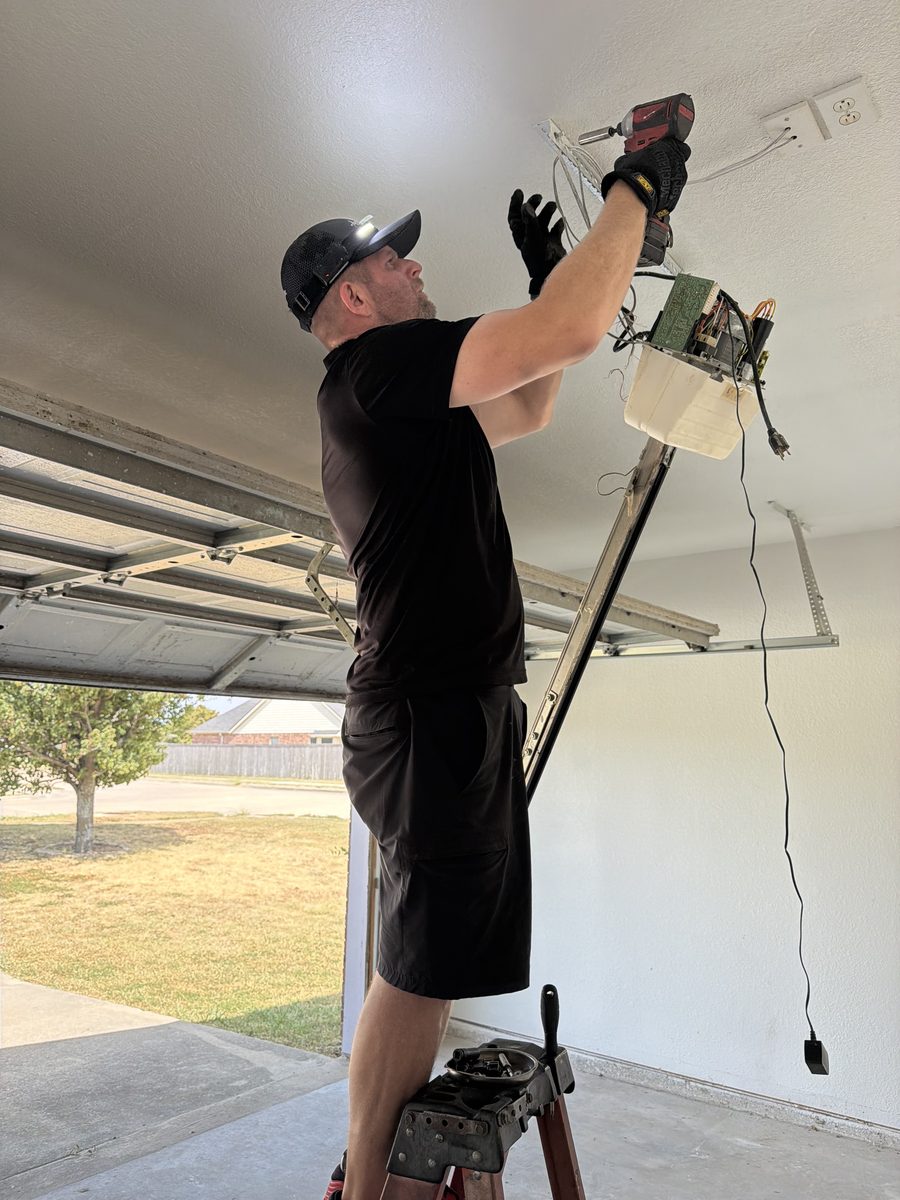 Technician on a ladder repairing an opener with the cover removed