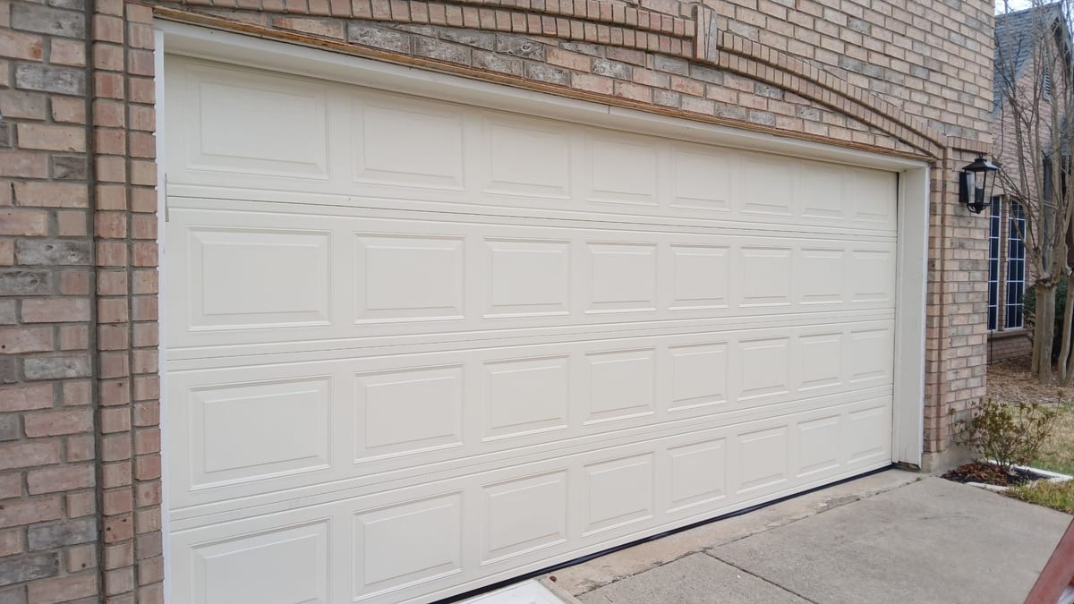 White raised short-panel garage door installed on a brick home