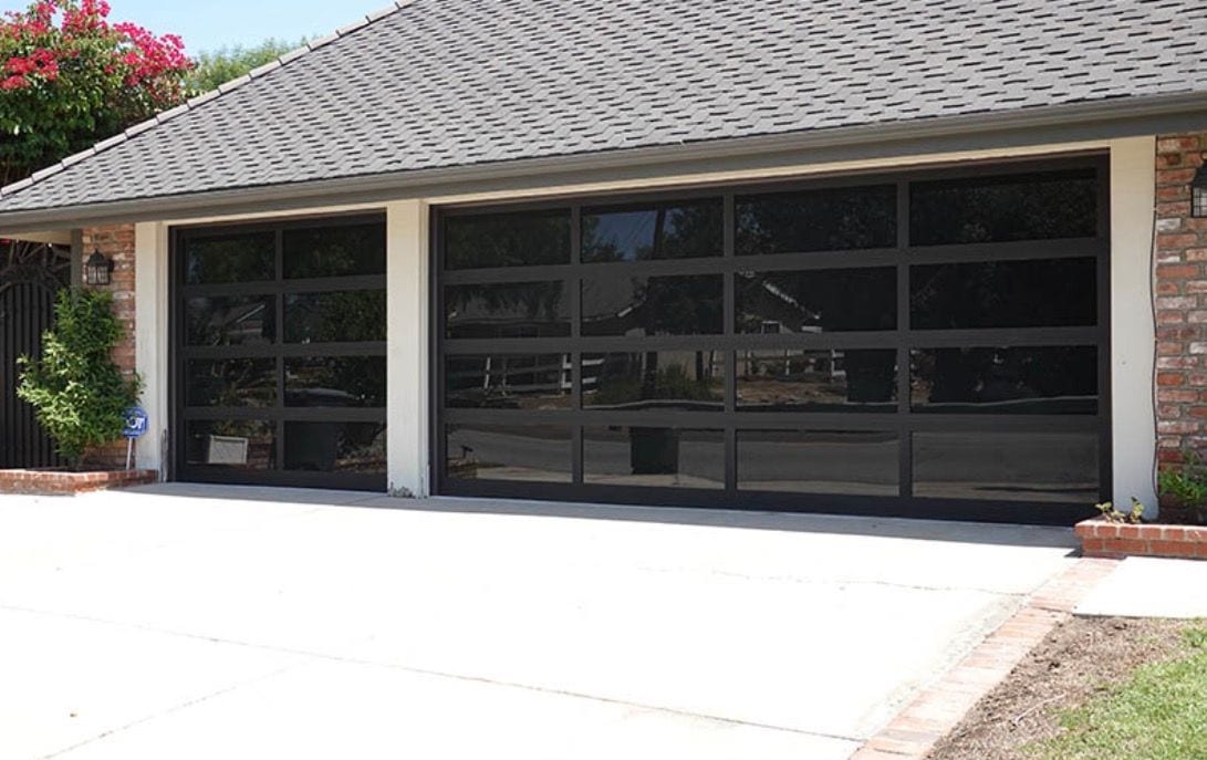 Black-framed full-view garage doors with dark tinted glass on a single-story home